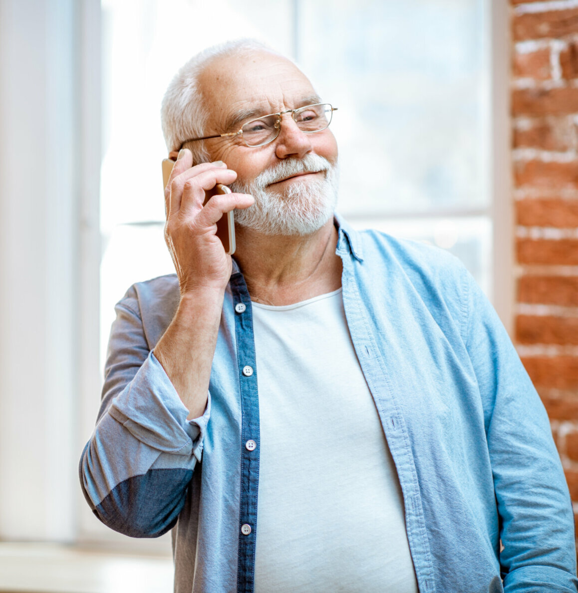 Senior gentleman making a mobile dental appointment by phone at home.