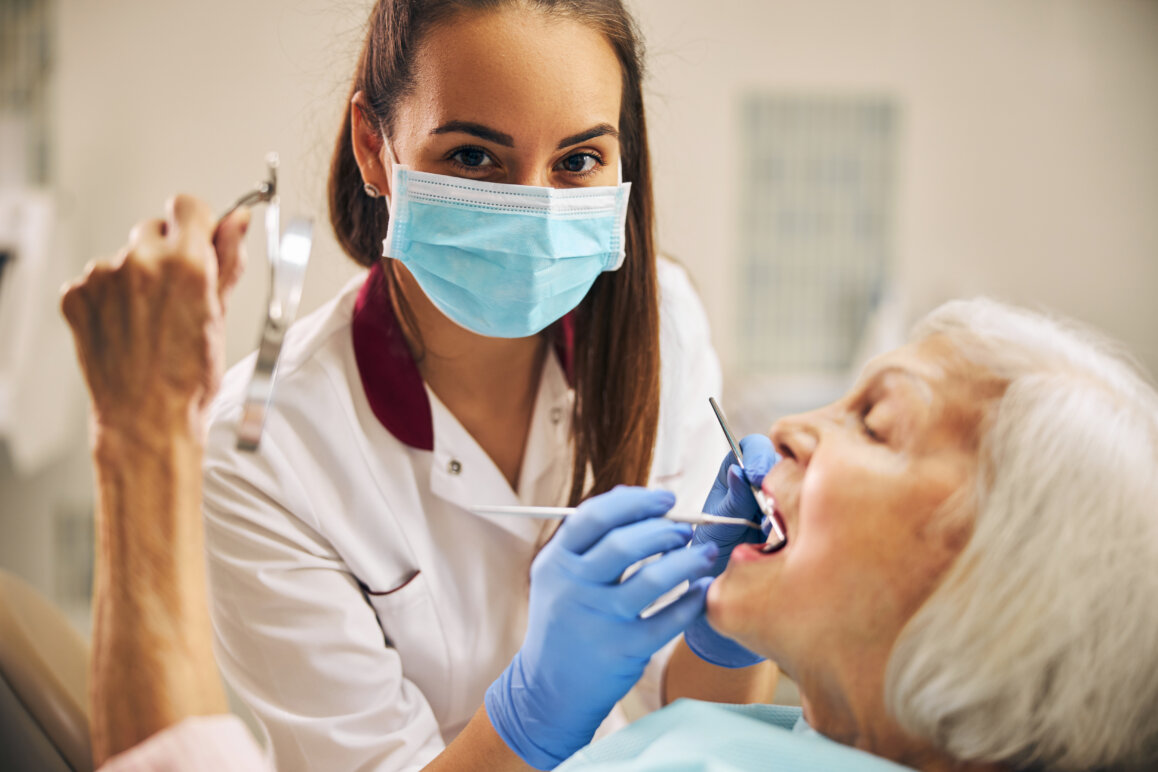 Female dentist treating female patient in dental chair at home.